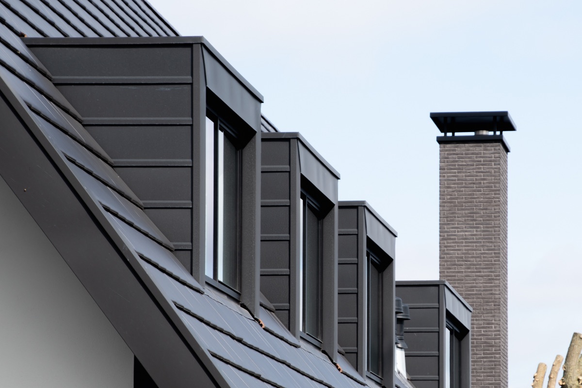 Detail van de dakkapellen en schoorsteen in zink en metselwerk