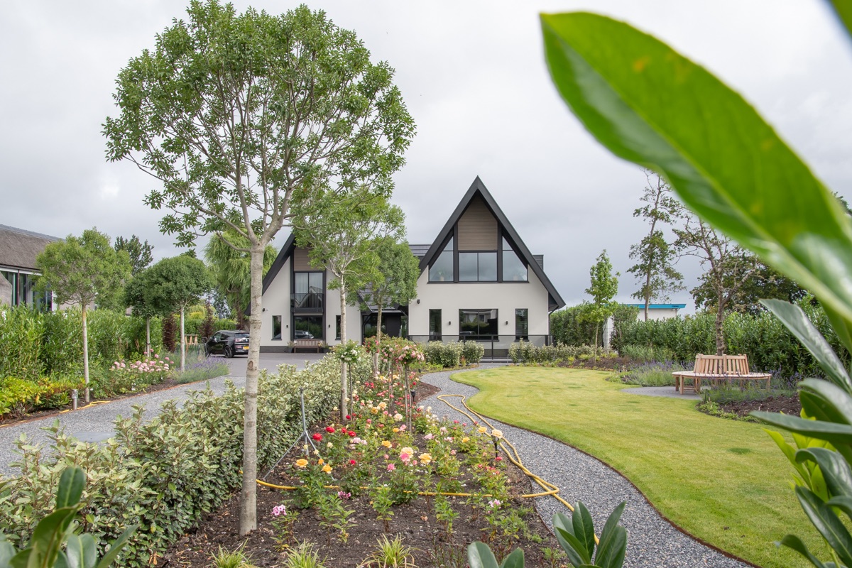 Aangelegde voortuin met beplanting en zicht op de woning